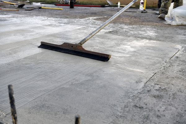 Smoothing a concrete parking lot and finishing with a concrete broom