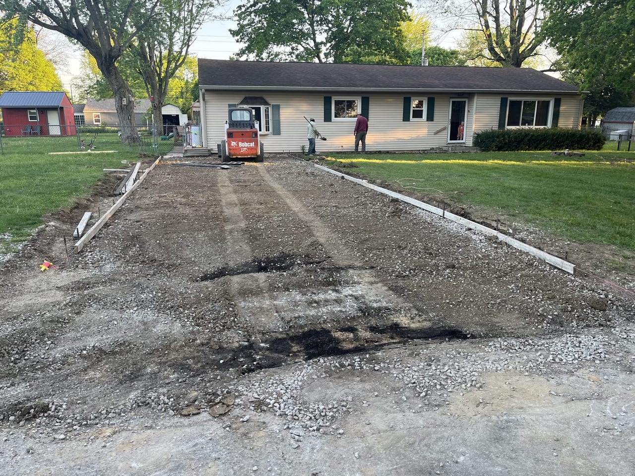 Skid-steer grading a compacted stone base for a new concrete driveway in Anderson, IN