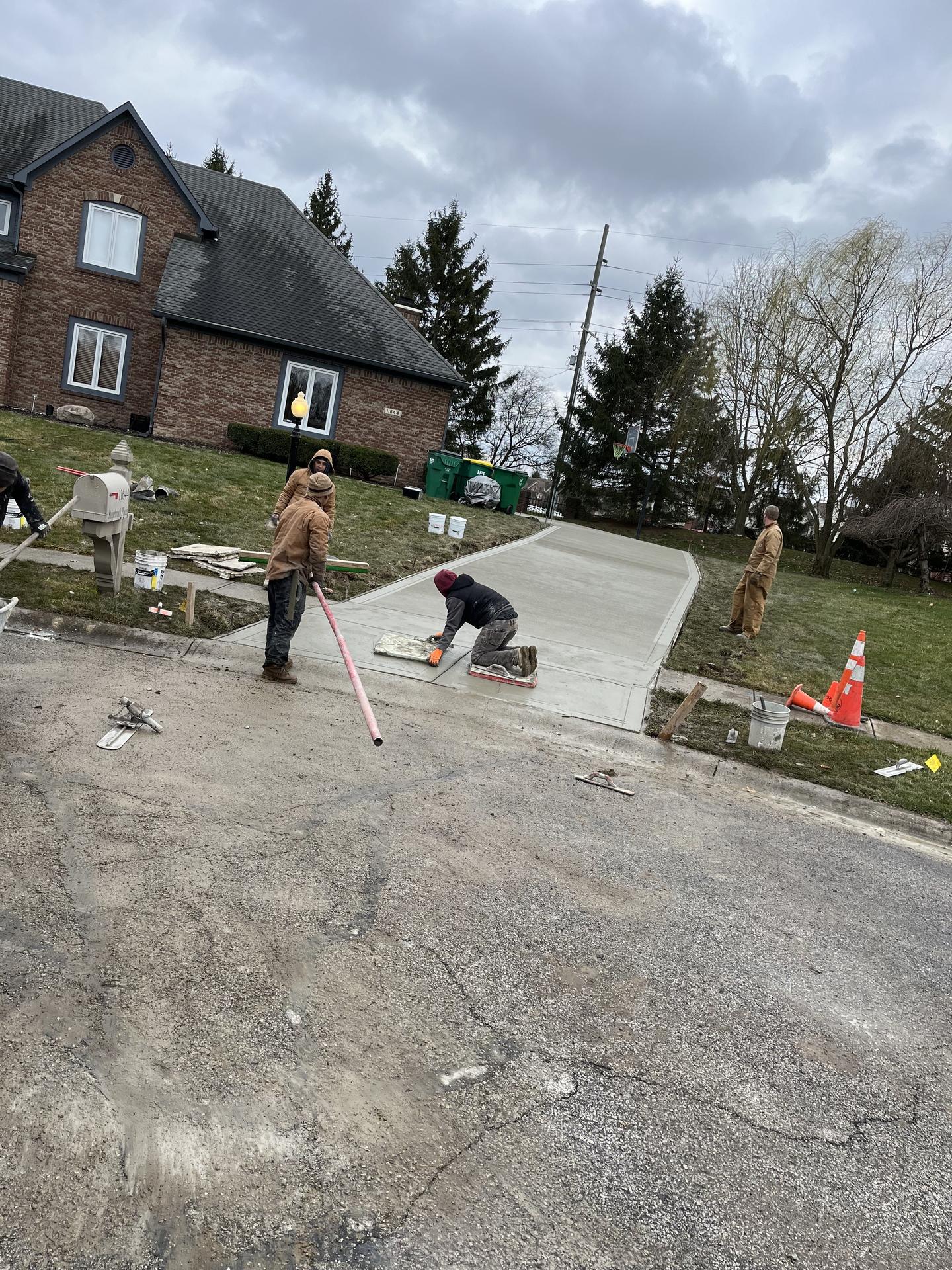Crew hand-finishing fresh concrete driveway slab, Zionsville Indiana