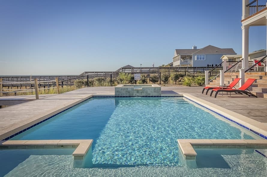 Beautiful blue pool with concrete pool deck overlooking the beach